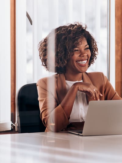 Person sits in office conference room in front of laptop.